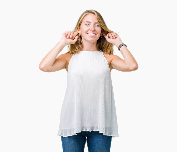 Красивая молодая элегантная женщина на изолированном фоне улыбаясь дергая за уши пальцами, смешной жест. Задача прослушивания
 - Фото, изображение
