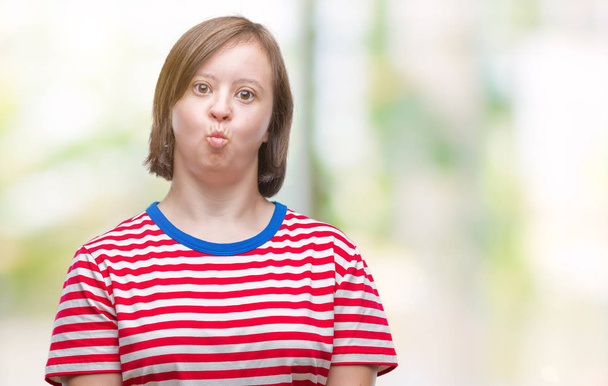 Mladé dospělé ženy s Downovým syndromem izolované pozadí nafoukla tváře s legrační obličej. Ústa naplněny vzduchem, šílený výraz. - Fotografie, Obrázek