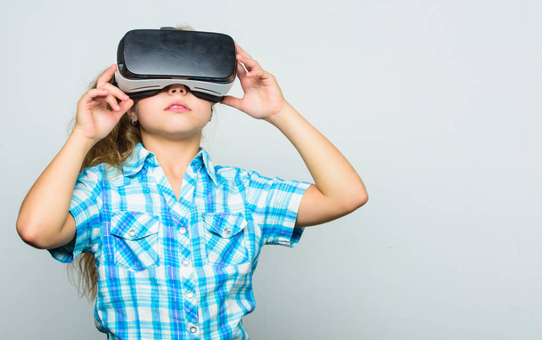 Little child in VR headset. Small child wear wireless VR glasses. Little girl wearing virtual reality goggles. Happy kid use modern technology. Digital future and innovation. Another reality is here - Photo, Image