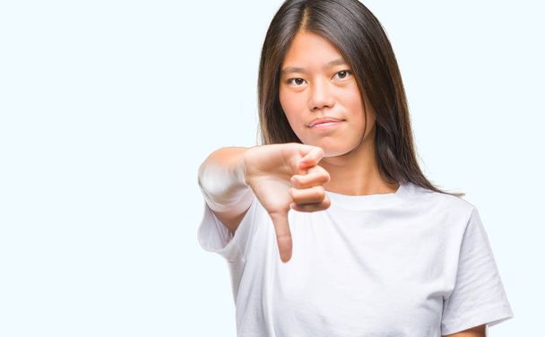 Jeune femme asiatique sur fond isolé regardant malheureux et en colère montrant rejet et négatif avec les pouces vers le bas geste. Mauvaise expression
. - Photo, image