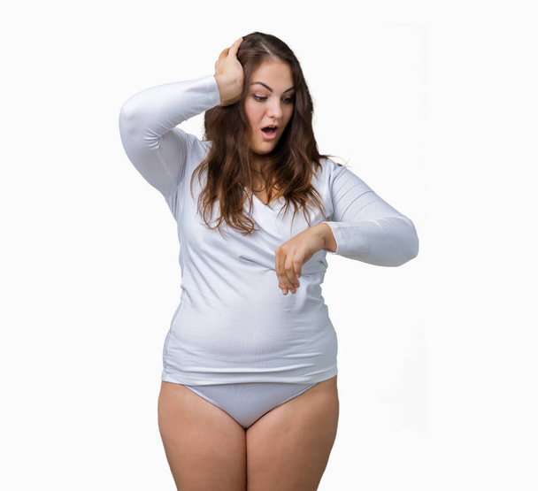 Beautiful plus size young overwight woman wearing white underwear over isolated background Looking at the watch time worried, afraid of getting late - Photo, Image