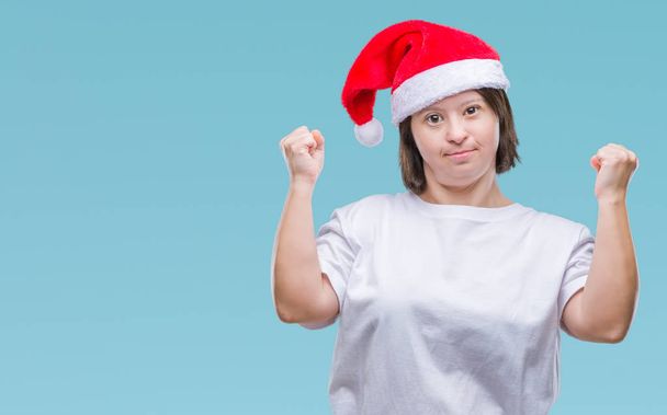 Mladé dospělé ženy s Downovým syndromem klobouk vánoční izolované pozadí velmi šťastný a nadšený, dělá vítěze gesto rukama zvedl, usmíval se a křičí na úspěch. Koncept oslav. - Fotografie, Obrázek