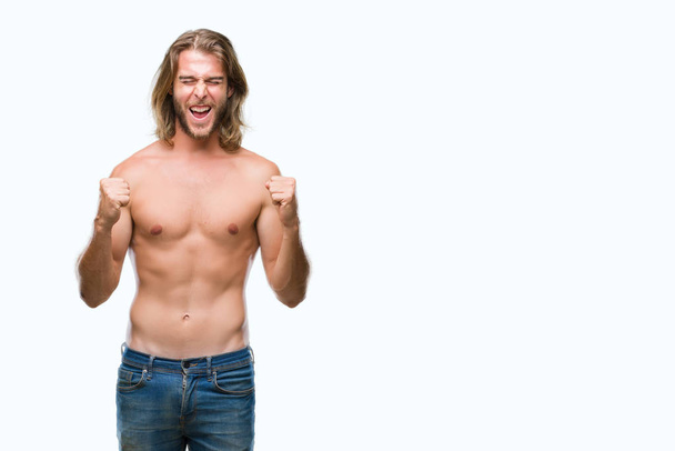 Fiatal jóképű félmeztelen férfi hosszú haj mutatja szexi test feletti elszigetelt háttér izgatott a siker karokkal emelt ünneplése győzelem mosolyogva. Győztes koncepció. - Fotó, kép