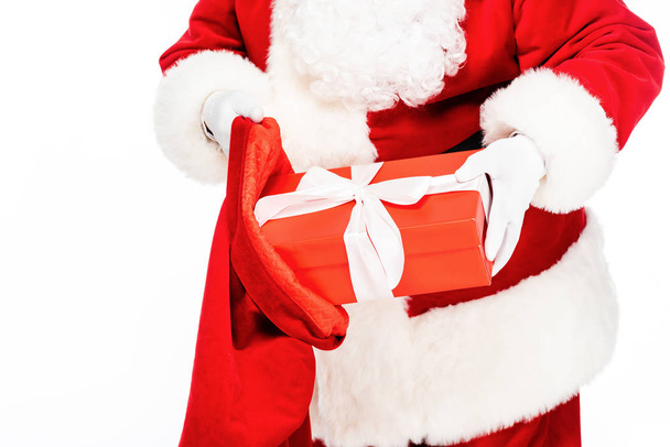 cropped shot of santa claus putting present into bag isolated on white - Valokuva, kuva