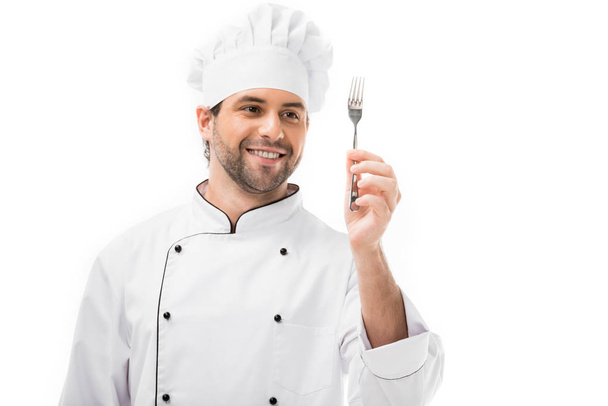 Lächelnder junger Koch hält Gabel isoliert auf weißem Grund - Foto, Bild