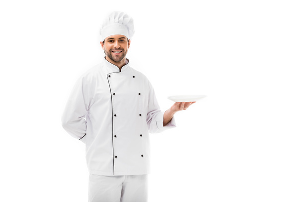schöner junger Koch mit leerem Teller und Blick in die Kamera isoliert auf weiß - Foto, Bild