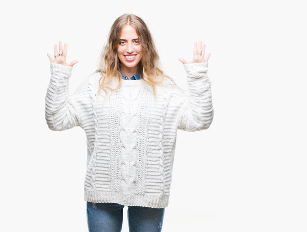 Красивая молодая блондинка в зимнем свитере на изолированном фоне показывает и указывает пальцами номер десять, улыбаясь уверенно и счастливо
. - Фото, изображение