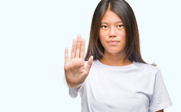 Fiatal ázsiai nő felett elszigetelt háttérben megáll énekelni a tenyerét a kezét. Figyelmeztetés kifejezés negatív és komoly gesztus az arcon. - Fotó, kép