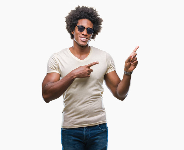 Afro american man wearing sunglasses over isolated background smiling and looking at the camera pointing with two hands and fingers to the side. - Valokuva, kuva