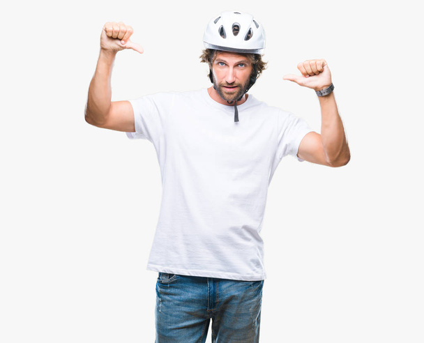 孤立した背景の顔に笑顔と自信を持って、誇りと幸せな指で自分を指して上安全ヘルメット身に着けているハンサムなヒスパニック系自転車男. - 写真・画像