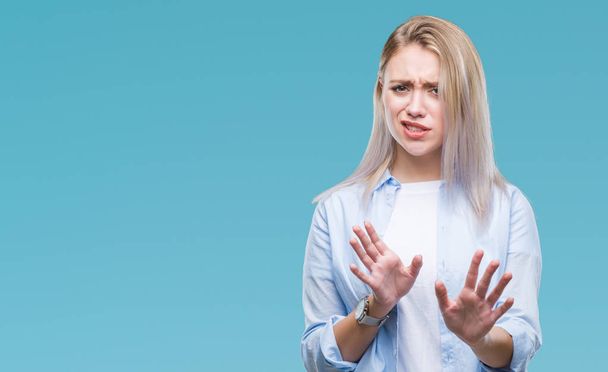 Young blonde woman over isolated background disgusted expression, displeased and fearful doing disgust face because aversion reaction. With hands raised. Annoying concept. - Foto, Imagem