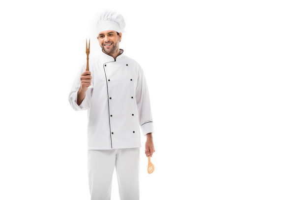 Lächelnder junger Koch mit hölzernem Küchengeschirr auf weißem Grund - Foto, Bild