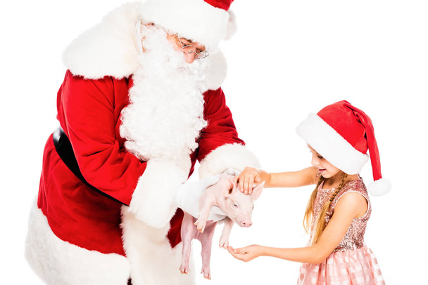 zbliże Świętego Mikołaja, dając piggy aby małe dziecko na białym tle - Zdjęcie, obraz