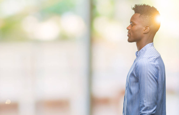 Jeune homme d'affaires afro-américain sur fond isolé regardant de côté, pose de profil relax avec visage naturel avec sourire confiant
. - Photo, image
