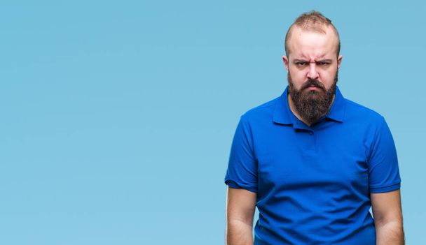 Молодой кавказский хипстер в голубой рубашке на изолированном фоне скептически и нервно, хмурясь расстроен из-за проблем. Отрицательное лицо
. - Фото, изображение