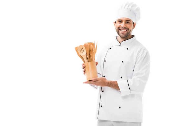 jeune chef souriant avec bouquet d'ustensiles de cuisine en bois isolés sur blanc
 - Photo, image