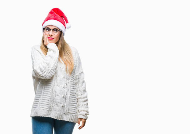 Νεαρή όμορφη γυναίκα που φοράει καπέλο Χριστουγέννων πάνω από απομονωμένες υπόβαθρο σκέψης ψάχνει κουρασμένη και τρυπημένο με προβλήματα κατάθλιψης με σταυρωμένα χέρια. - Φωτογραφία, εικόνα