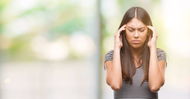 Jonge mooie Spaanse vrouw met hand op het hoofd voor pijn in hoofd omdat stress. Lijden van migraine. - Foto, afbeelding