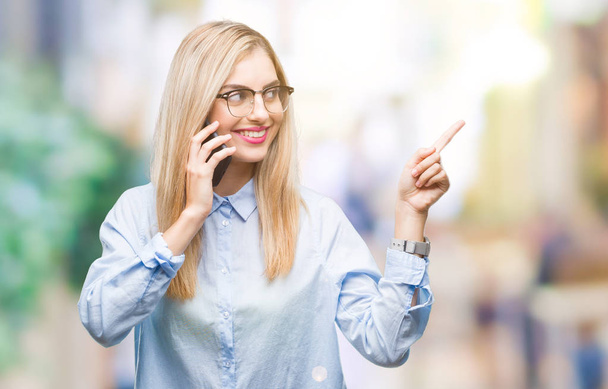 junge schöne blonde Geschäftsfrau ruft Smartphone über isolierten Hintergrund sehr glücklich zeigt mit Hand und Finger zur Seite - Foto, Bild