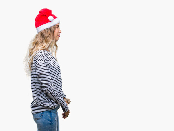 Beautiful young blonde woman wearing christmas hat over isolated background looking to side, relax profile pose with natural face with confident smile. - Fotografie, Obrázek