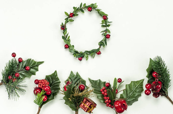 Christmas New Year holidays composition: green holiday wreath, five green branches, red berries and gift on white background with copy space for your text. Red star: We wish you a Merry Christmas. - Foto, Imagen