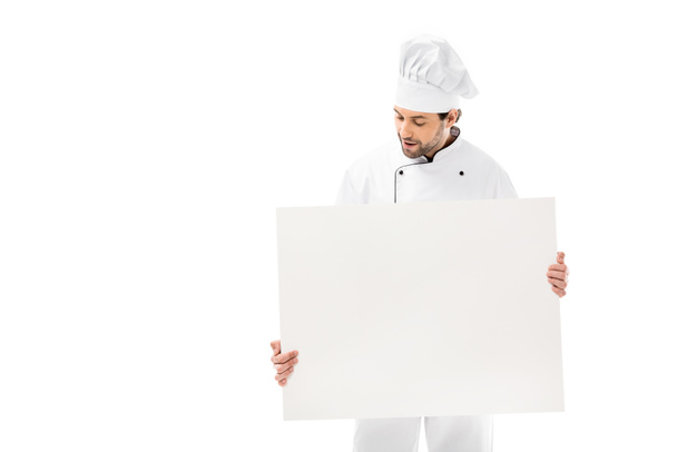 joven chef profesional sosteniendo pancarta en blanco y mirando hacia abajo aislado en blanco
  - Foto, imagen