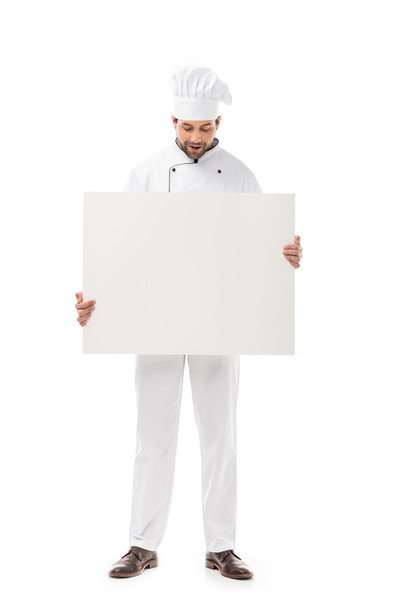 professional male cook holding blank banner and looking down isolated on white  - Fotoğraf, Görsel