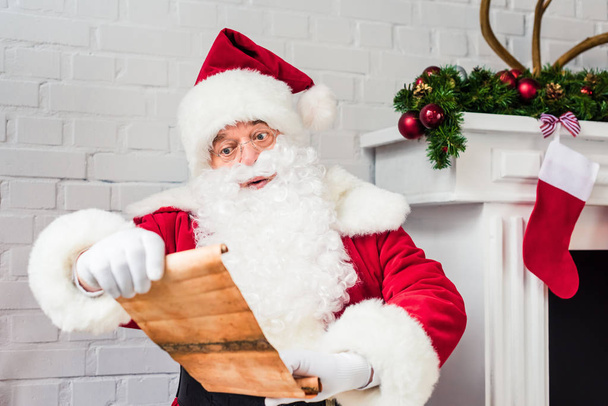 Санта Клаус тримає пергамент і читає список побажань
 - Фото, зображення