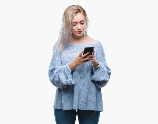 Sarışın genç kadın manifatura acımak yüz ciddi düşünüyorum üstünde kendine güvenen bir ifade ile izole arka plan üzerinde Smartphone kullanarak ileti gönderme - Fotoğraf, Görsel