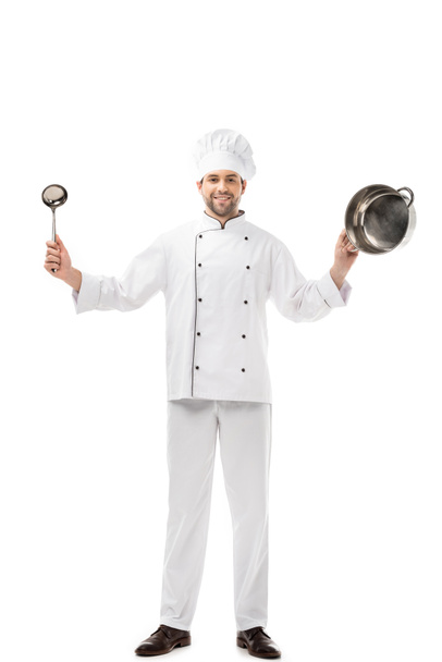 handsome smiling chef holding ladle and pan isolated on white - Foto, immagini
