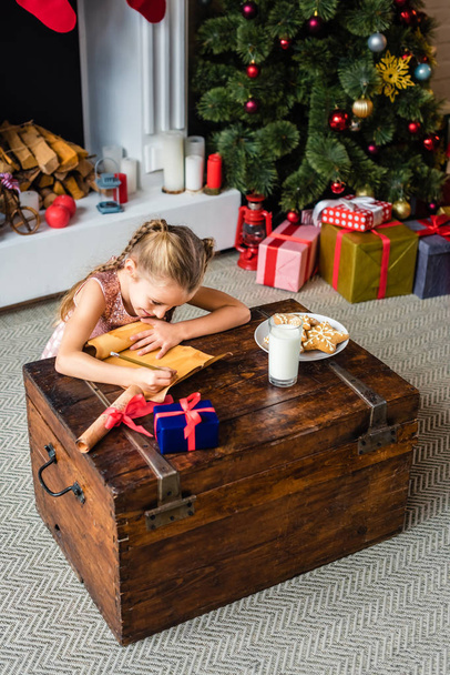 high angle view of adorable little child writing wishlist on parchment at christmas time - Photo, Image
