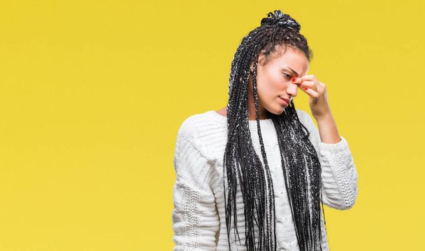 Young braided hair african american girl wearing sweater over isolated background tired rubbing nose and eyes feeling fatigue and headache. Stress and frustration concept. - 写真・画像