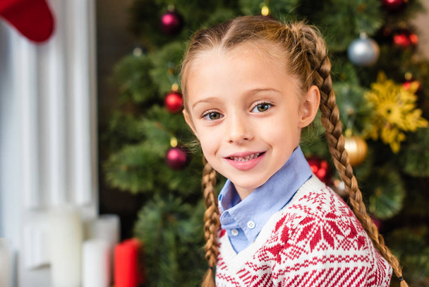 портрет очаровательного счастливого ребенка, улыбающегося в камеру во время Рождества
  - Фото, изображение
