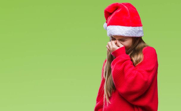 Jeune belle fille portant un chapeau de Noël sur fond isolé fatigué se frottant le nez et les yeux ressentant fatigue et maux de tête. Concept de stress et de frustration
. - Photo, image
