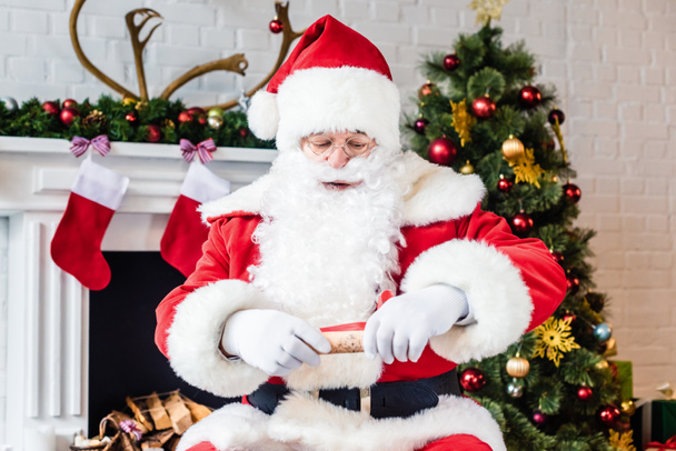 Babbo Natale azienda rotolato pergamena con lista dei desideri
 - Foto, immagini