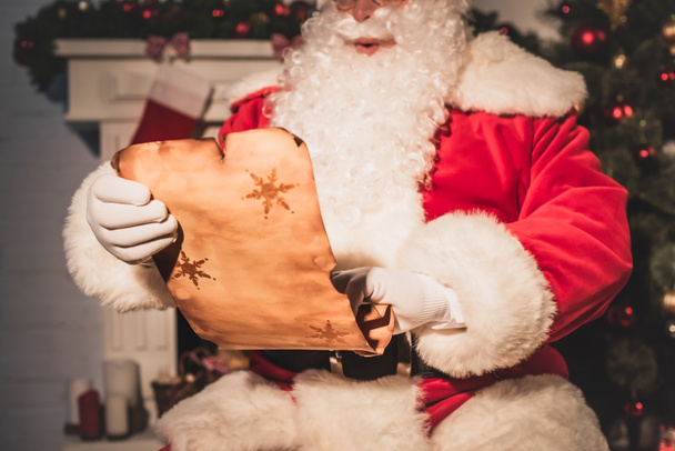 cropped shot of santa claus holding parchment with wishlist - Photo, Image