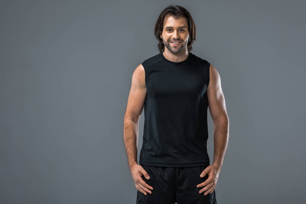 portrait of handsome athletic young man in sportswear smiling at camera isolated on grey - Φωτογραφία, εικόνα