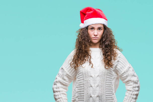 Young brunette girl wearing christmas hat over isolated background with serious expression on face. Simple and natural looking at the camera. - Fotoğraf, Görsel
