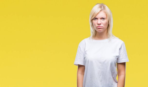 Mladá krásná blondýna žena nosí bílé tričko izolované pozadí skeptik a nervózní, mračil se naštvaná kvůli problému. Negativní osoba. - Fotografie, Obrázek