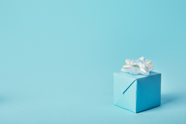 Mavi zemin üzerine beyaz Fiyonklu hediye kutusu - Fotoğraf, Görsel