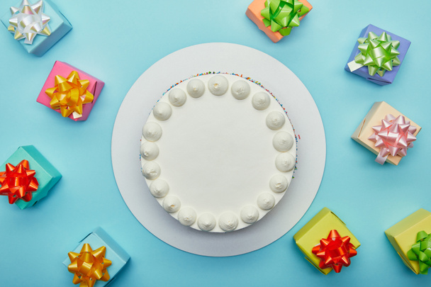 Vista superior de delicioso pastel y regalos sobre fondo azul
 - Foto, Imagen