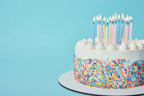 Delicioso pastel de cumpleaños con velas encendidas sobre fondo azul
 - Foto, imagen
