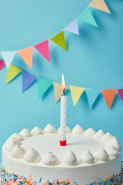 Candle on tasty birthday cake on blue background with bunting - Photo, Image