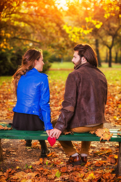 Пара держащих сердечную форму на скамейке в парке
. - Фото, изображение