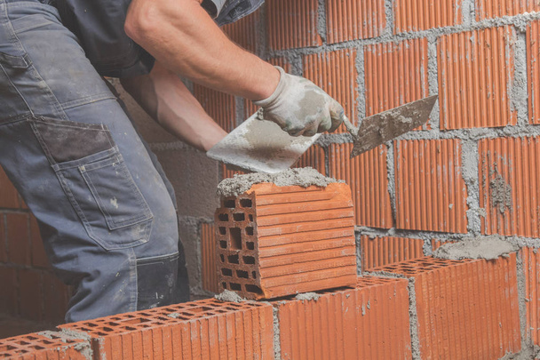 Trabalhador da construção real tijolo que coloca a parede dentro de casa
. - Foto, Imagem