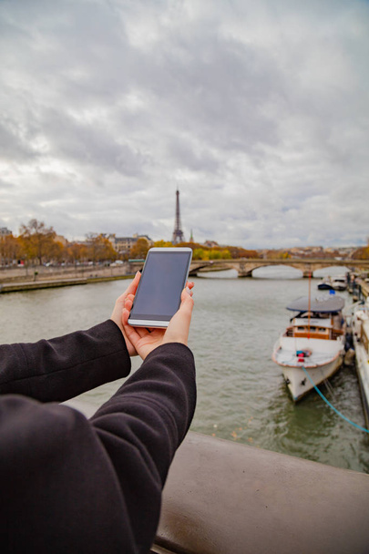 Paris geçmişi ve Eyfel kulesi olan cep telefonu kullanan bir kız.. - Fotoğraf, Görsel