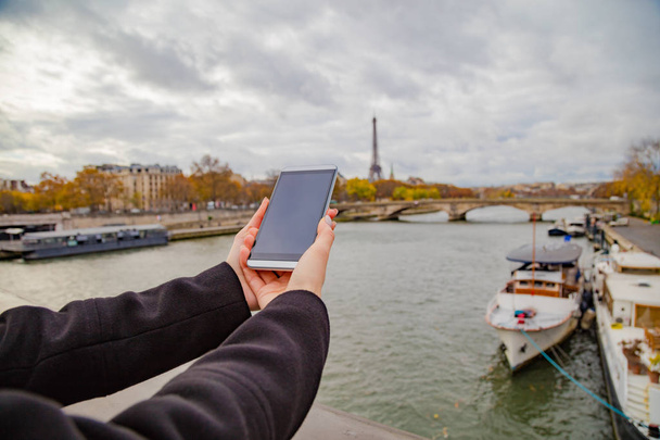 Κορίτσι που χρησιμοποιεί κινητό τηλέφωνο με φόντο το Παρίσι και τον πύργο του Άιφελ. - Φωτογραφία, εικόνα