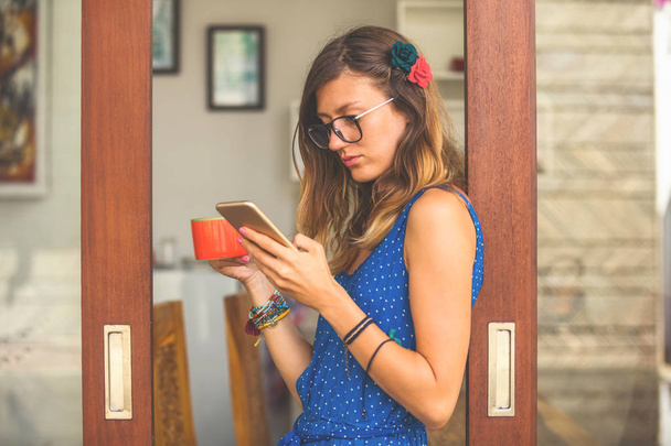 Жінка використовує мобільний телефон і п'є каву всередині квартири вікно, скло, відображення
. - Фото, зображення