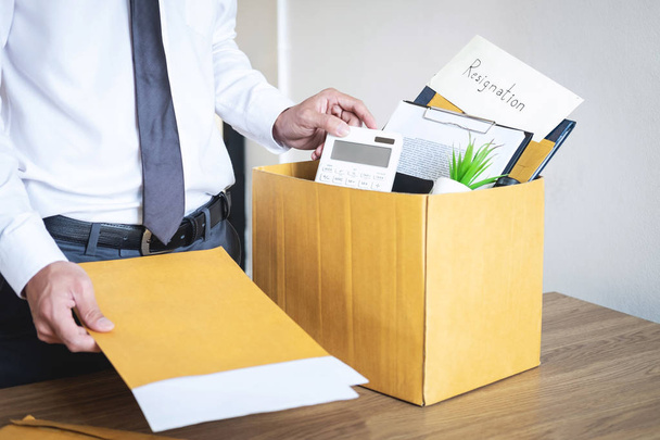 Businessman sending letter will being resignation and carrying packing belongings company and files into brown cardboard box, changing and resigning from work concept. - Фото, изображение