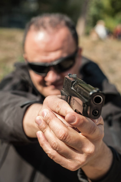 Police agent and bodyguard pointing pistol to protect from attacker. Gun point aiming front view outdoor - Foto, Imagen
